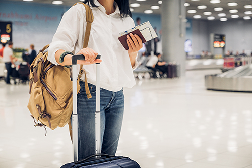 Woman backpacker holding passport and map with suitcase standing at check in baggage at airport terminal,traveler concept.